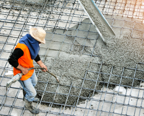 Construction Worker Spreading Concrete Into Place