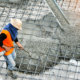 Construction Worker Spreading Concrete Into Place